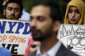 People hold signs while attending a rally to protest the New York Police Department's surveillance tactics near its headquarters in New York on August 28, 2013 [AP/Seth Wenig]