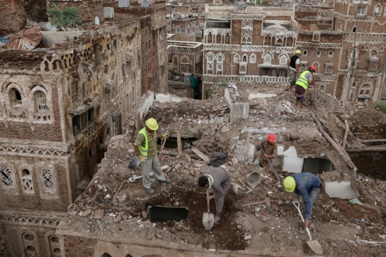 Workers demolish a building damaged by rain in the UNESCO World Heritage site of the old city of Sanaa
