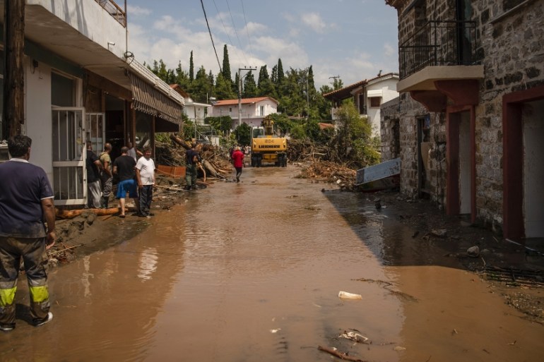 People stand in a destroyed street following a storm at the village of Politika, on Evia island, northeast of Athens, on August 9, 2020. Five people including a baby died and two more were missing as