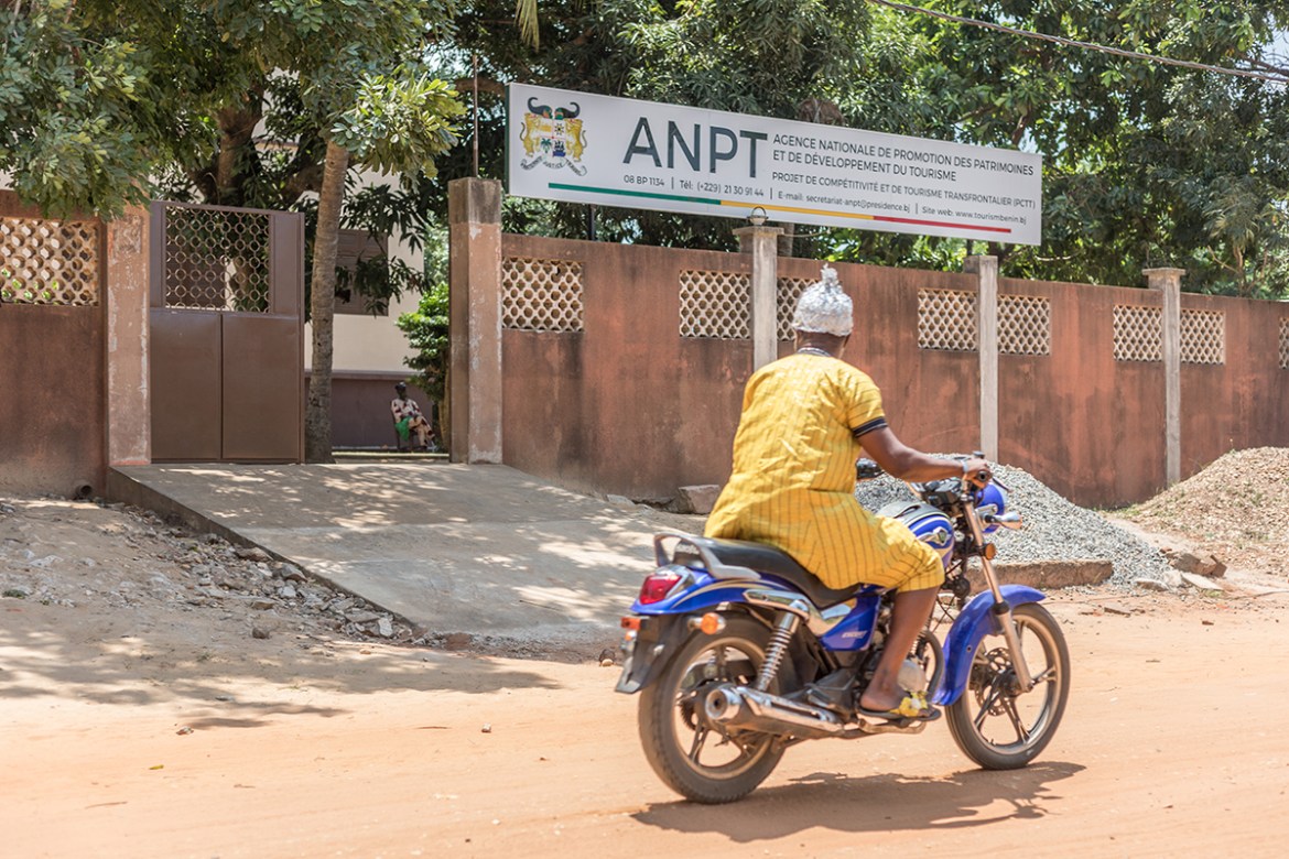 A man drives on a motorcycle past the house of Brazil in Ouidah, where the exhibition on the kingdom of Savi can be seen, in Ouidah on August 4, 2020. - As western cities see statues of slaveholders a