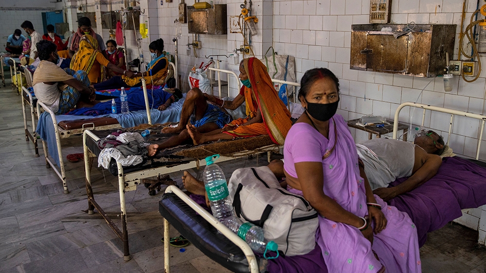 COVID-19 patient Parsada Sah, 67, a shopkeeper, lies on a hospital bed as his wife Vimla Devi, 62, sits next to him in the emergency ward as they wait for Sah to be transferred to the Intensive Care U