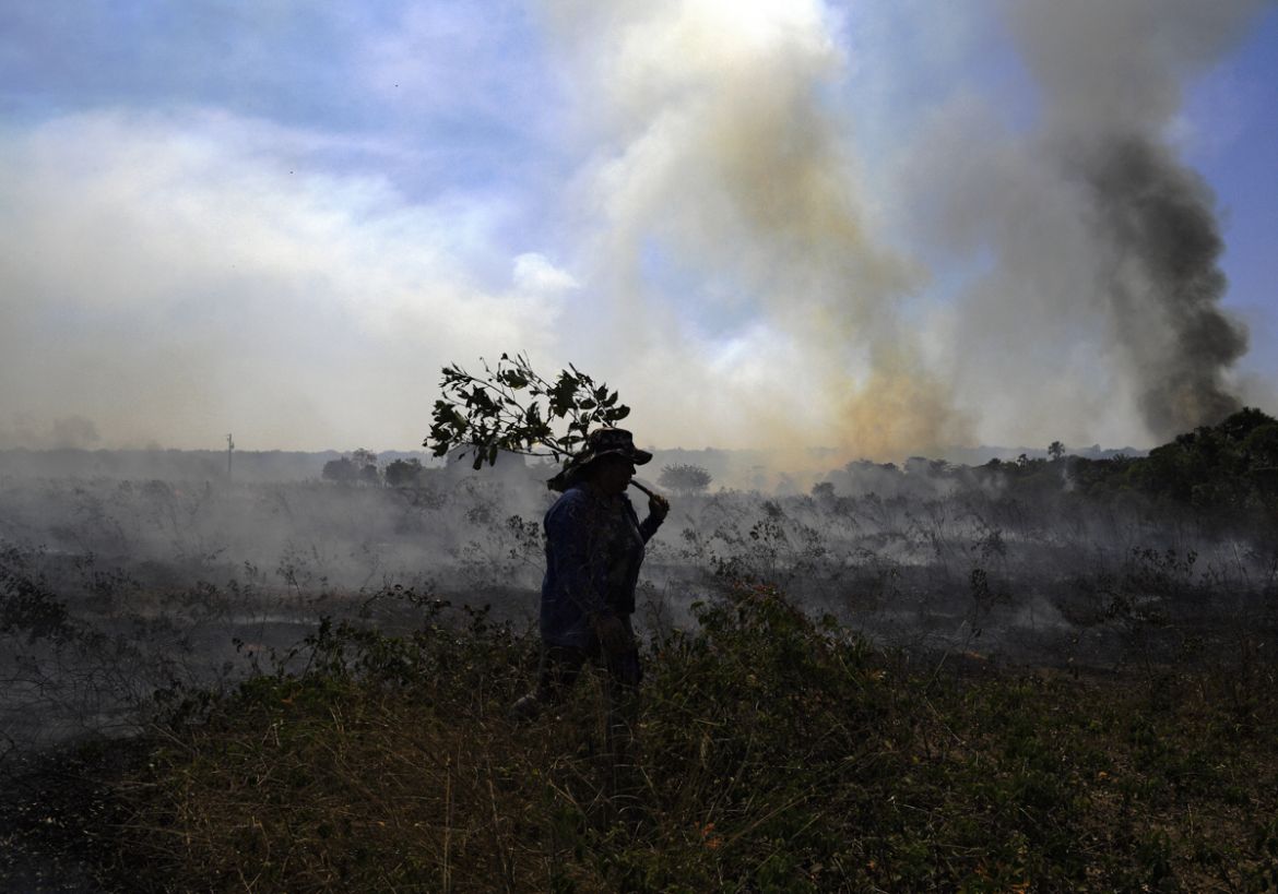 A farm worker tries to put out an illegal fire which burned part of the Amazon rainforest reserve and was spreading to their land north of Sinop, in Mato Grosso State, Brazil, on August 10, 2020. (Pho