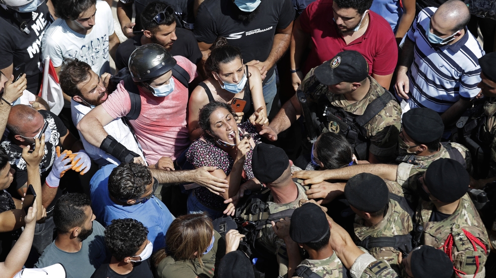 A woman yells at Lebanese soldiers during scuffles with the soldiers who are blocking a road as French President Emmanuel Macron visits the Gemmayzeh neighborhood, which suffered extensive damage from