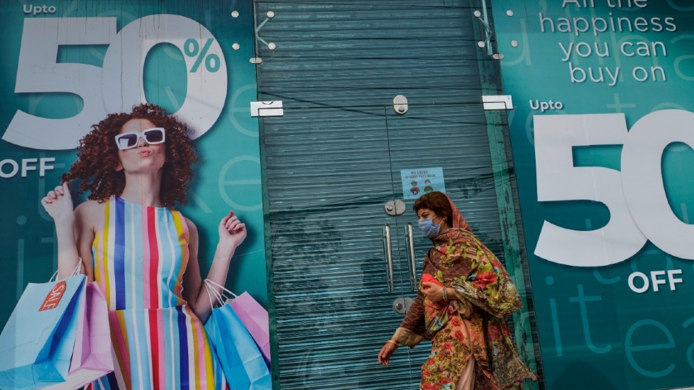 A woman walks past a shuttered market in Rawalpindi on July 29, 2020, after the Punjab province government announced a lockdown closing markets, shopping malls and