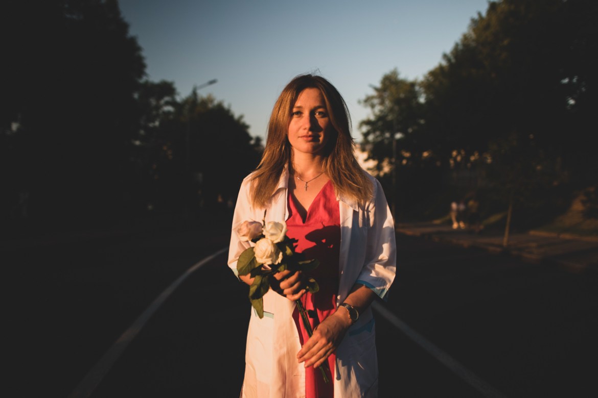 Tatyana, 29, an ambulance paramedic poses for a photo holding white roses during an opposition rally near Independence Square in Minsk, Belarus, Monday, Aug. 17, 2020. Behind each protester in Belarus