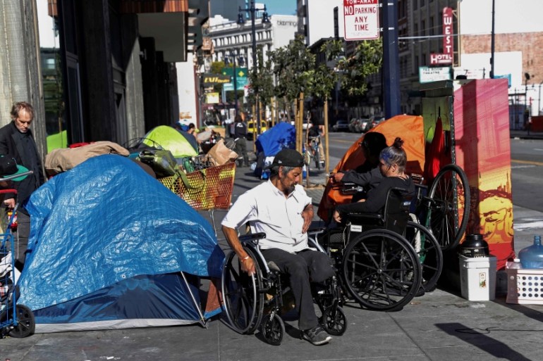 People line in a sidewalk filled with tents set up by the homeless, amid an outbreak of the coronavirus disease (COVID-19), in the Tenderloin district of San Francisco,