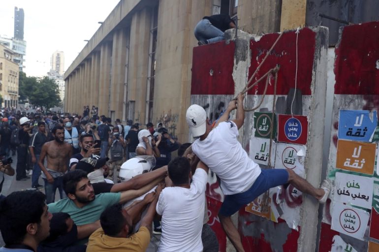 Protesters try to remove a concrete slab from a barrier to open a road leading to the parliamen