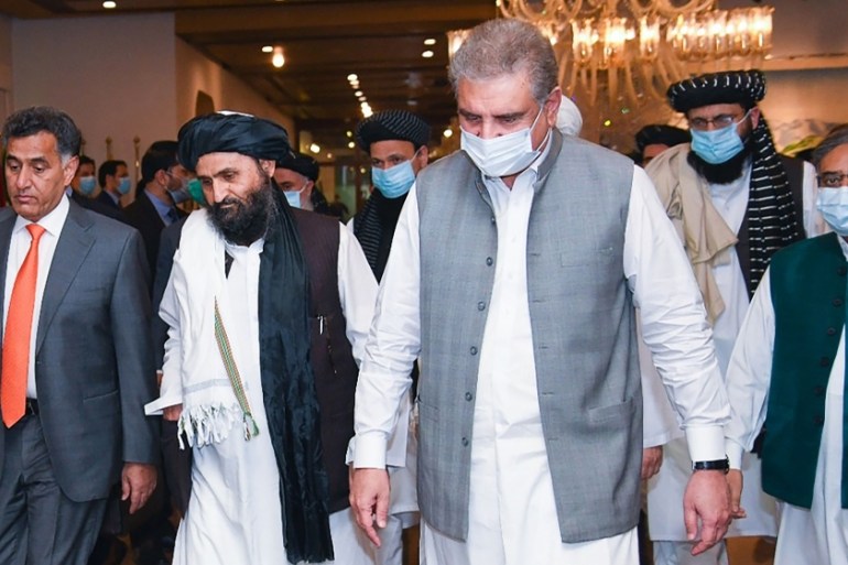 In this handout photograph taken on August 25, 2020, and released by the Pakistan Foreign Ministry, Pakistan''s Foreign Minister Shah Mehmood Qureshi (3R) walks with Taliban co-founder Mullah Abdul Gha