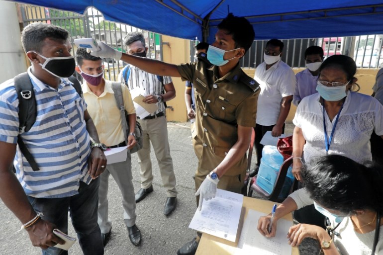 A health official takes the temperature of election officials in Colombo