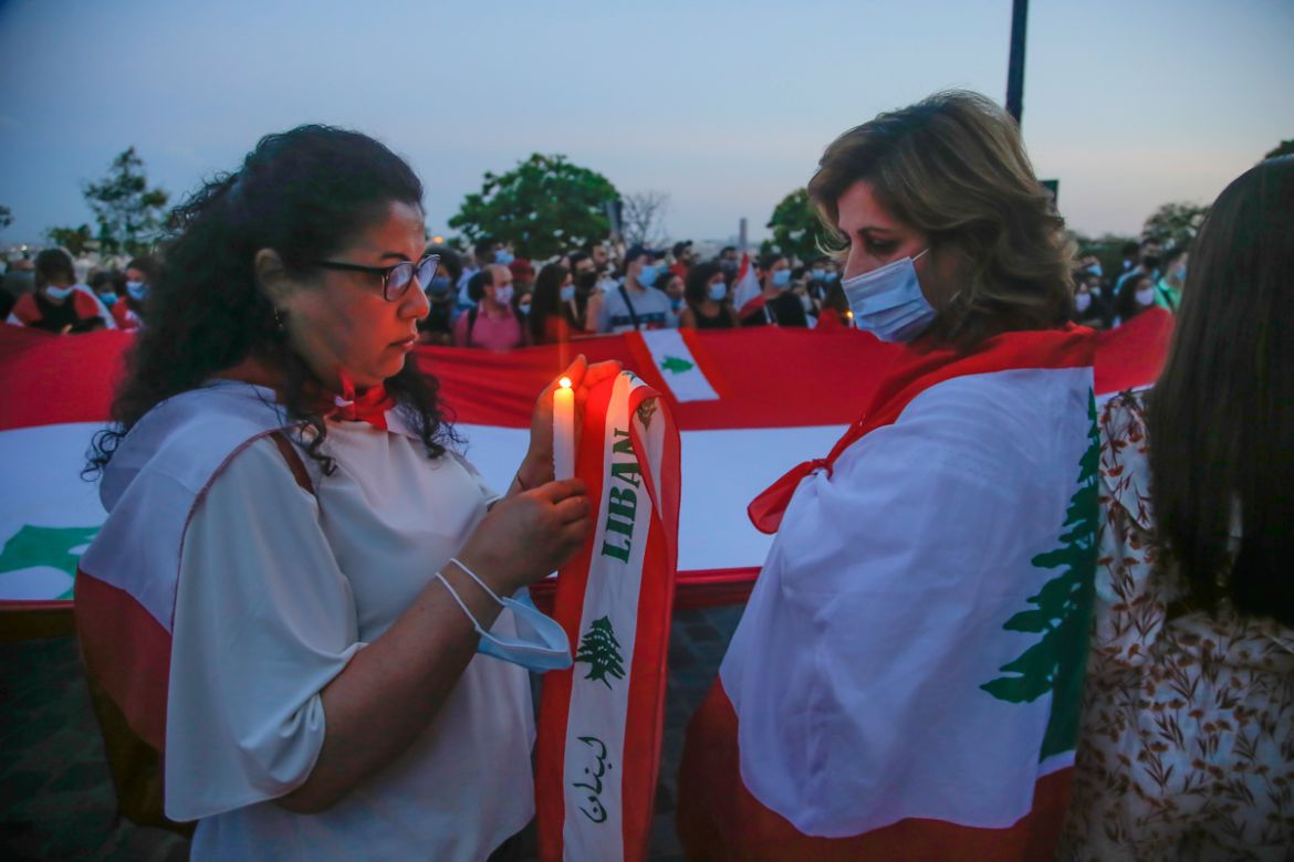 A woman of the Lebanese community holds a candle during a vigil in memory of victims of the deadly blast in Beirut in front of Sacre Coeur Basilica in Paris, Wednesday, Aug. 5, 2020. French President