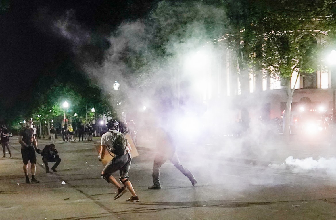 epa08623699 Protestors run as police launch teargas during a second night of unrest in the wake of the shooting of Jacob Blake by police officers, in Kenosha, Wisconsin, USA, 24 August 2020. According