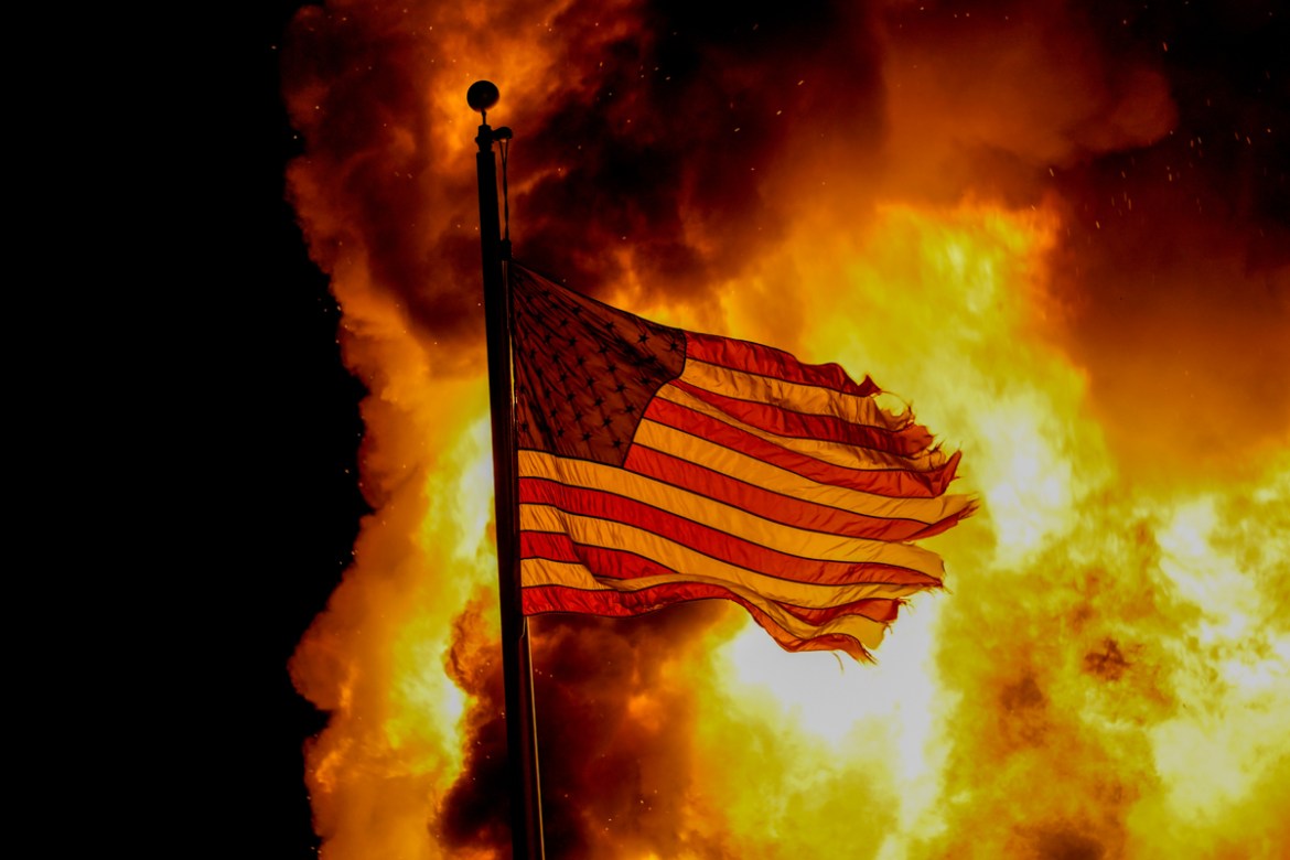 A flag flies over a department of corrections building that was on fire during protests, Monday, Aug. 24, 2020, in Kenosha, Wis., sparked by the shooting of Jacob Blake by a Kenosha Police officer a d