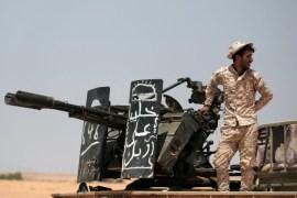 A member of the Libyan National Army (LNA) commanded by Khalifa Haftar stands on a military vehicle at one of their sites in west of Sirte