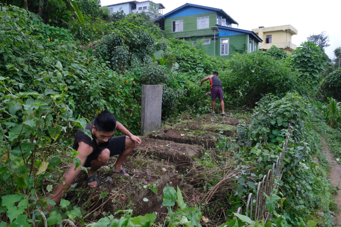 Angami Naga boys clear weed from the graves of 8 children, killed in 1976 when a World War II-era bomb exploded while they were playing, in Kohima village, the site of a bloody battle between the Japa