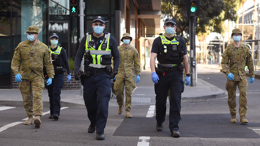 A group of police and soldiers patrol the Docklands area of Melbourne on August 2, 2020, after the announcement of new restrictions to curb the spread of the COVID-19 coronavirus. - Australia on Augus