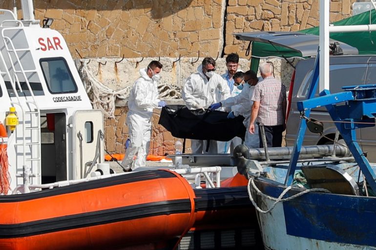 Emergency services carry a body at the dock of Le Castella after a migrant boat caught fire during rescue operations off the coast of Crotone, with some people still missing according to Italian media