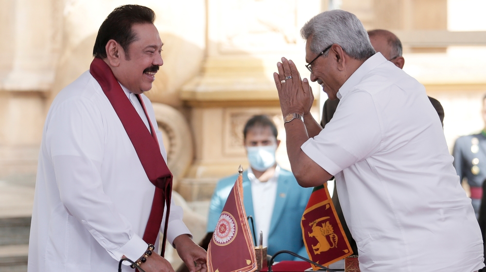Sri Lanka's former leader Mahinda Rajapaksa and his brother, and Sri Lanka's President Gotabaya Rajapaksa gesture during the swearing in ceremony at Kelaniya Buddhist temple in Colombo