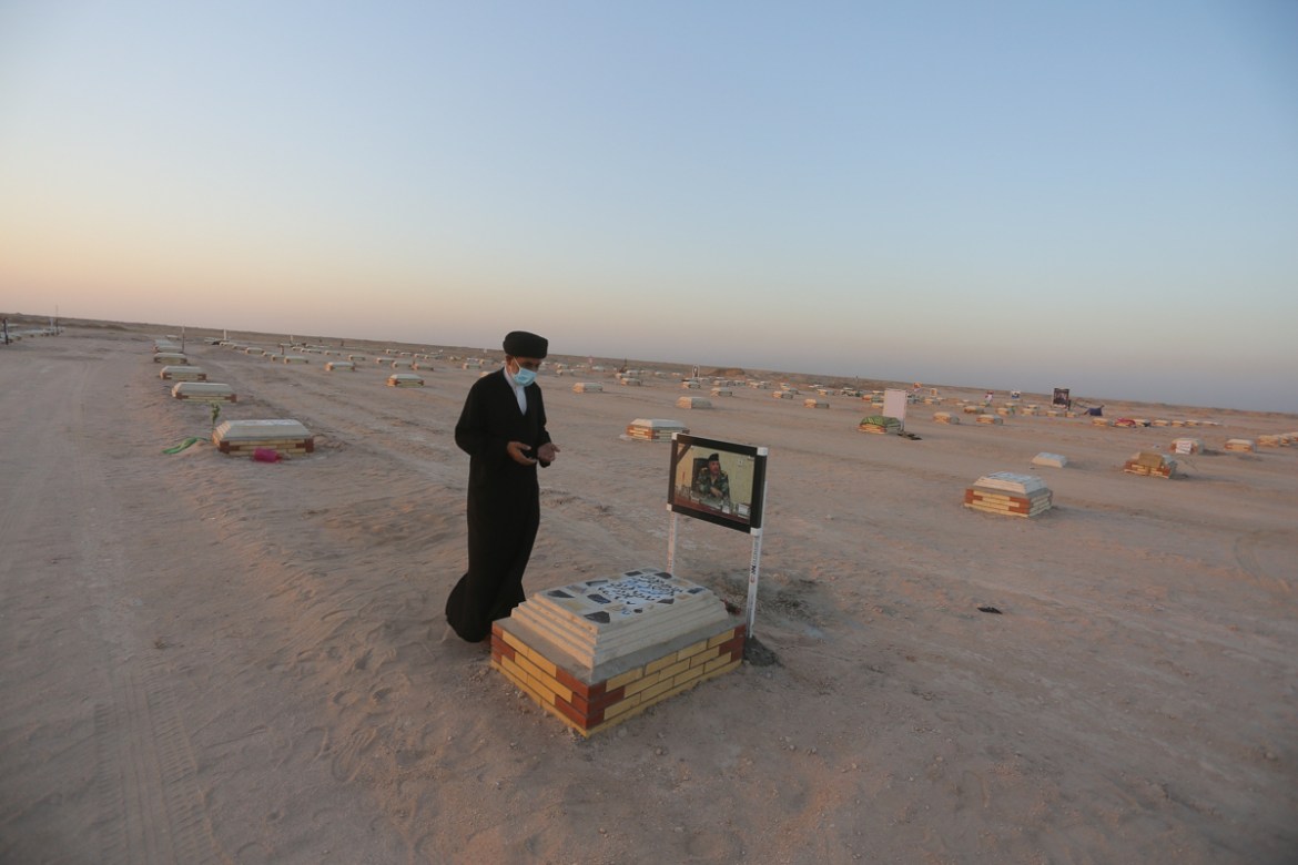 Shiite cleric prays by the grave of coronavirus victim at Wadi al-Salam cemetery near Najaf, Iraq, Sunday, July 19, 2020. A special burial ground near the Wadi al-Salam cemetery has been created speci