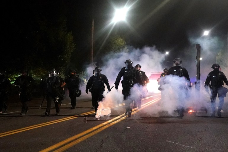 Portland police officers walk through clouds of smoke while dispersing a crowd from in front of the Multnomah County Sheriffs Office on August 22, 2020 in Portland, Oregon. Hundreds of protesters clas