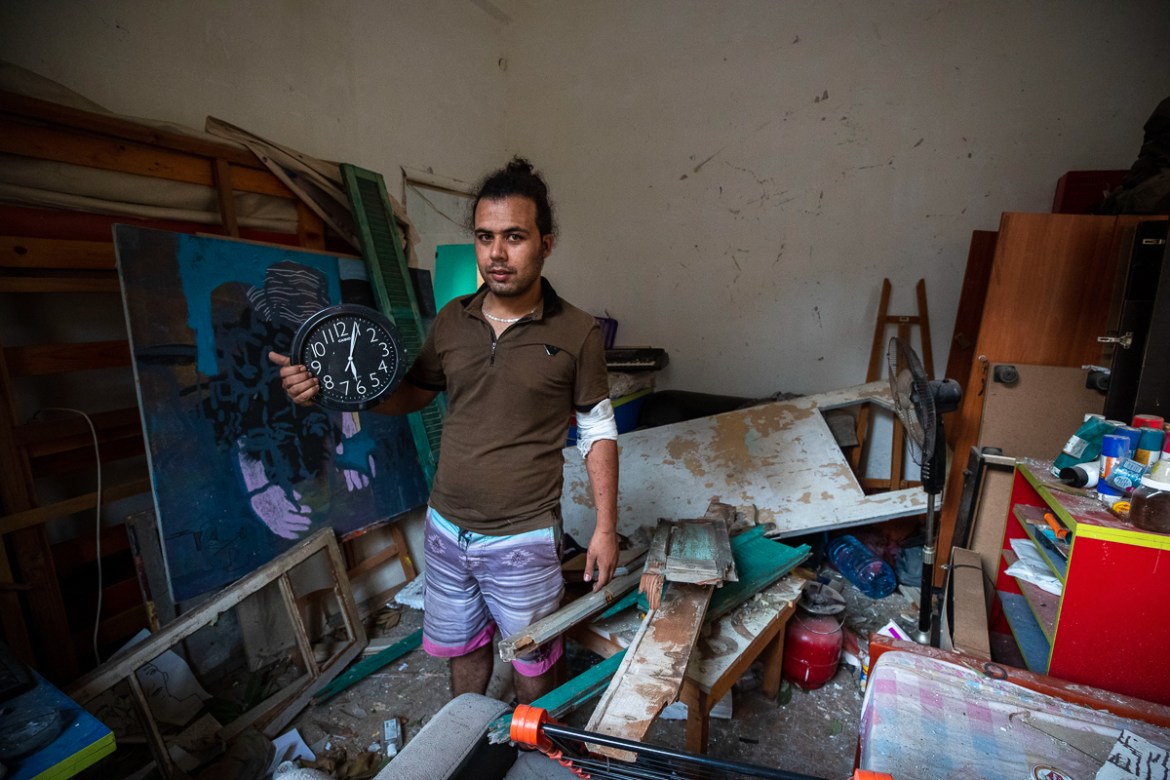 Hasan Al Armali, holds a wall clock that was stoped working at the time of the Tuesday''s explosion in the seaport of Beirut, poses for a photograph at his bedroom inside his destroyed apartment, in Be