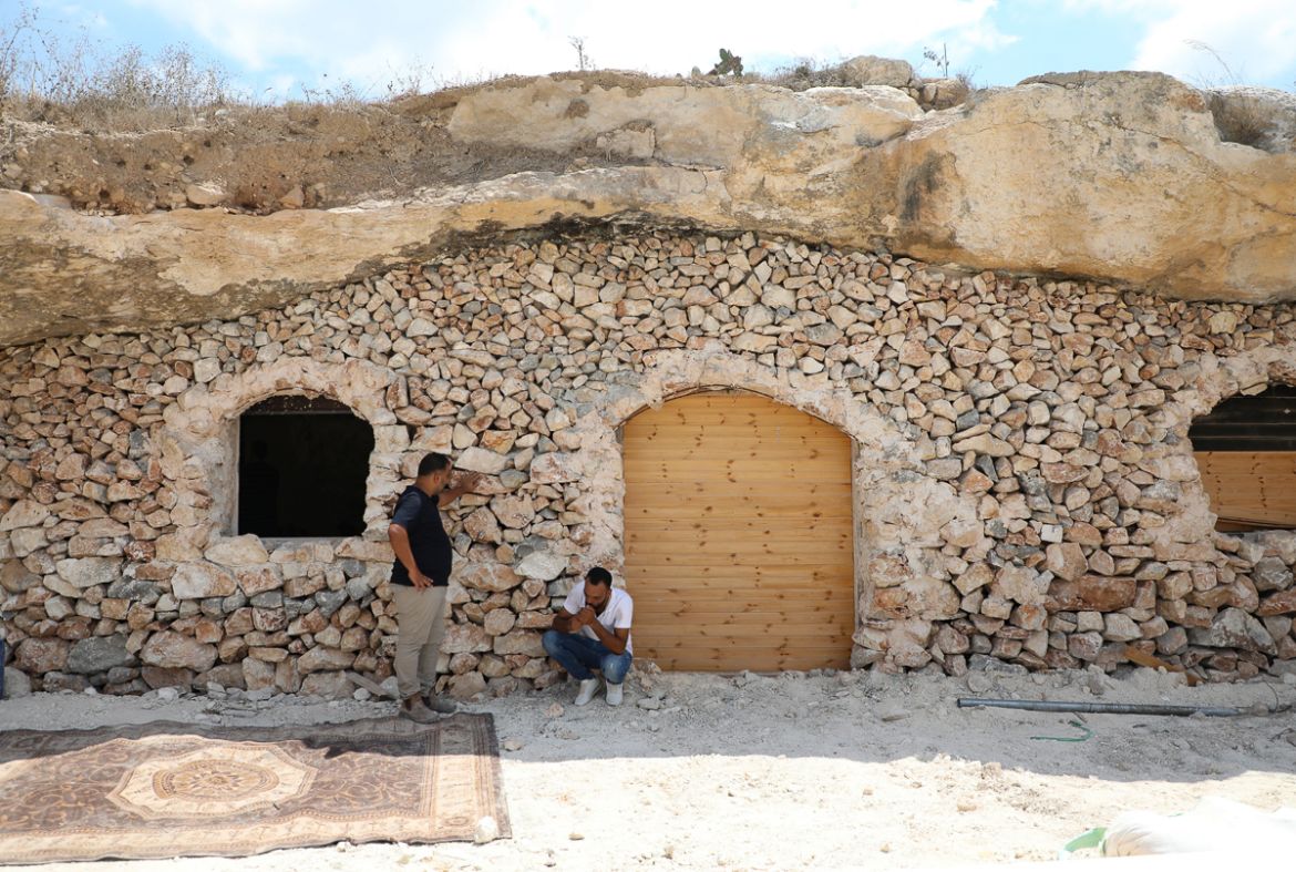 Ahmed Amarneh and a neighbour chat outside his home, built in cave in the village of Farasin, west of Jenin, in the northern occupied West Bank on August 4, 2020. - Amarneh, a 30 year old civil engine