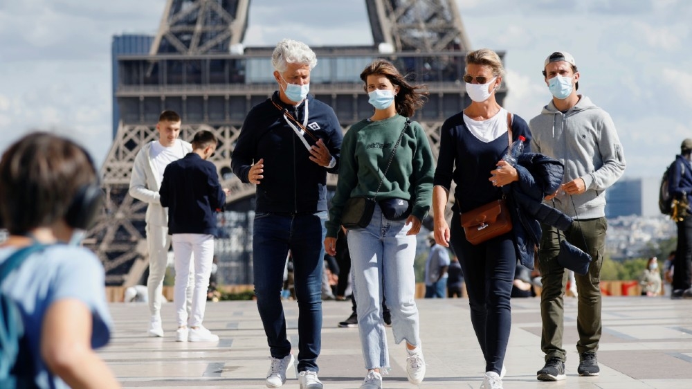 People wearing protective masks walk at the Trocadero square near the Eiffel Tower as France reinforces mask-wearing as part of efforts to curb a resurgence of the coronavirus disease