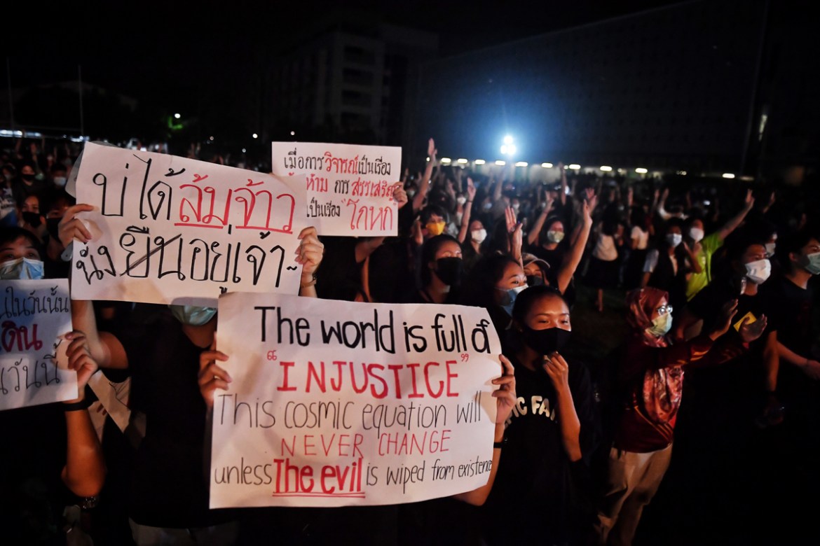 Student protesters hold signs as they flash the three-fingered Hunger Games salute during an anti-government rally at Mahidol University in Nakhon Pathom on August 18, 2020. - The country has seen nea
