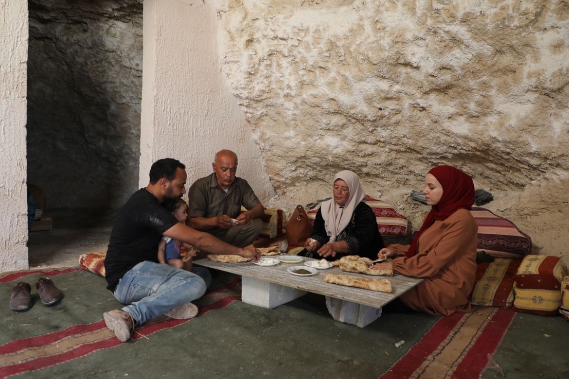 Ahmed Amarneh (L), and family members share a meal at his home built in cave, in the village of Farasin, west of Jenin, in the northern occupied West Bank on August 4, 2020. - Amarneh, a 30 year old c