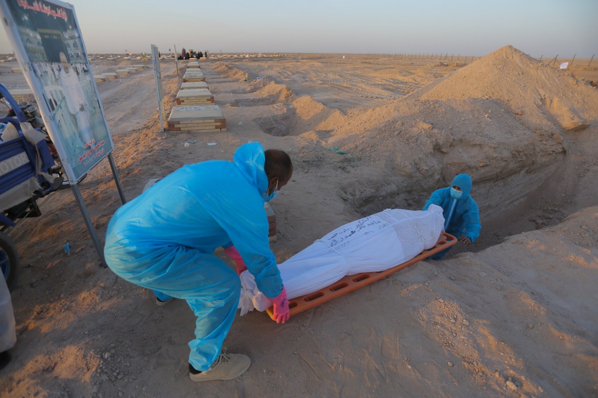 Members of the Shiite Imam Ali brigades militia bury a body of a coronavirus victim during a funeral at Wadi al-Salam cemetery near Najaf, Iraq, Monday, July 20, 2020. A special burial ground near the