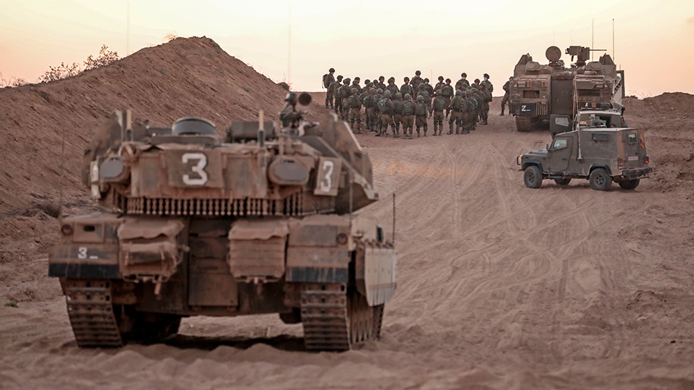 Israeli infantry soldiers gather next to tanks and an armoured personnel carrier near the Israeli border with the Gaza Strip, on August 16, 2020. (Photo by MENAHEM KAHANA / AFP)