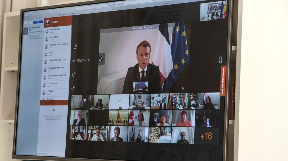 A handout photo made available by the office of the prime minister of Spain (La Moncloa) shows French President Emmanuel Macron (on screen) participates via a video connection with world leaders about