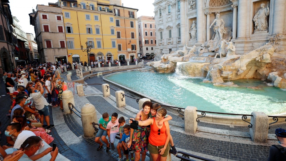 People not wearing face masks take selfies in front of the Trevi Fountain following a government decree that states face coverings must be worn between 6 p.m. and 6 a.m. near bars