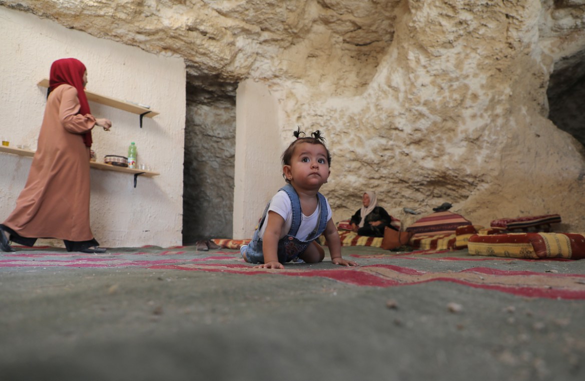 The daughter of Ahmed Amarneh crawls on a carpet at his home built in cave, in the village of Farasin, west of Jenin, in the northern occupied West Bank on August 4, 2020. - Amarneh, a 30 year old civ
