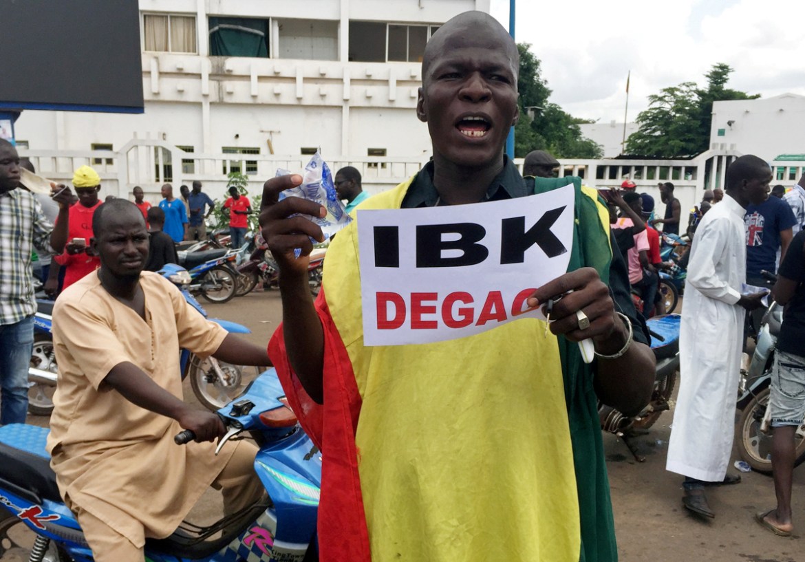 An opposition supporter holds a sign reading ''IBK (President Ibrahim Boubacar Keita), get out,'' in reaction to the news of a possible mutiny of soldiers in the military base in Kati, outside the capit