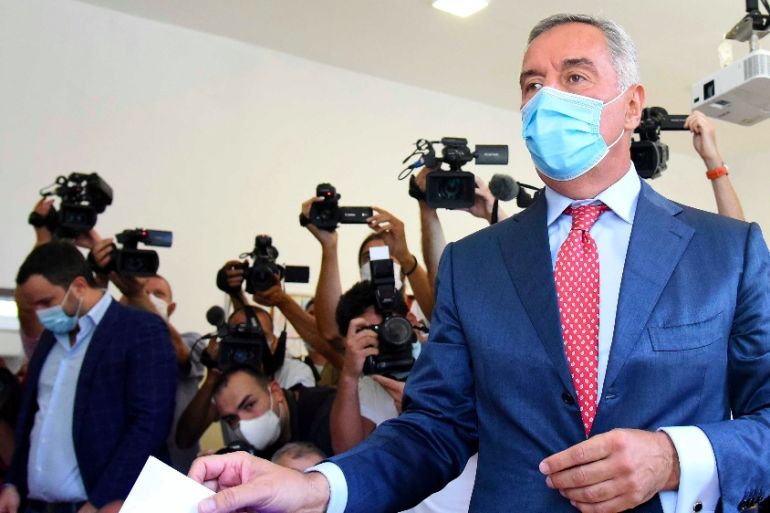 Montenegrin President Milo Djukanovic wearing a mask against the spread of the new coronavirus casts his ballot to vote in parliamentary elections at a polling station in Podgorica, Montenegro