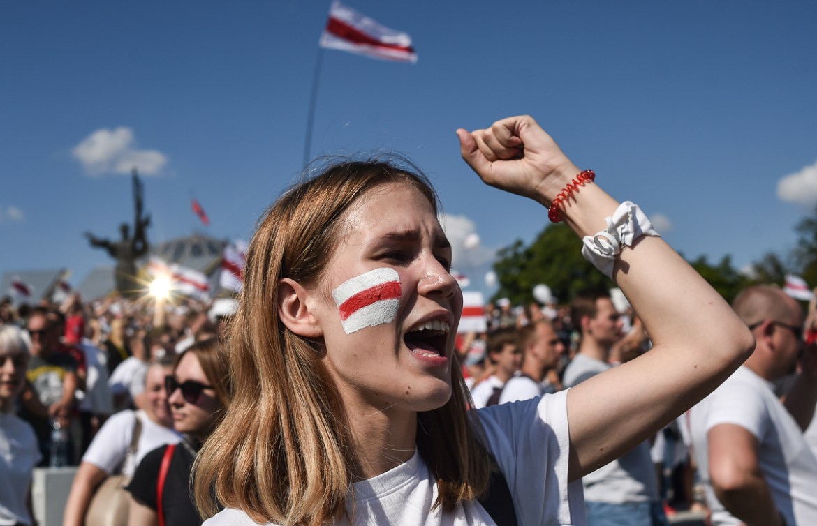 A woman Belarus opposition supporter with a drawing of a former white-red-white flag of Belarus used in opposition to the government punches the air during a demonstration in central Minsk on August 1