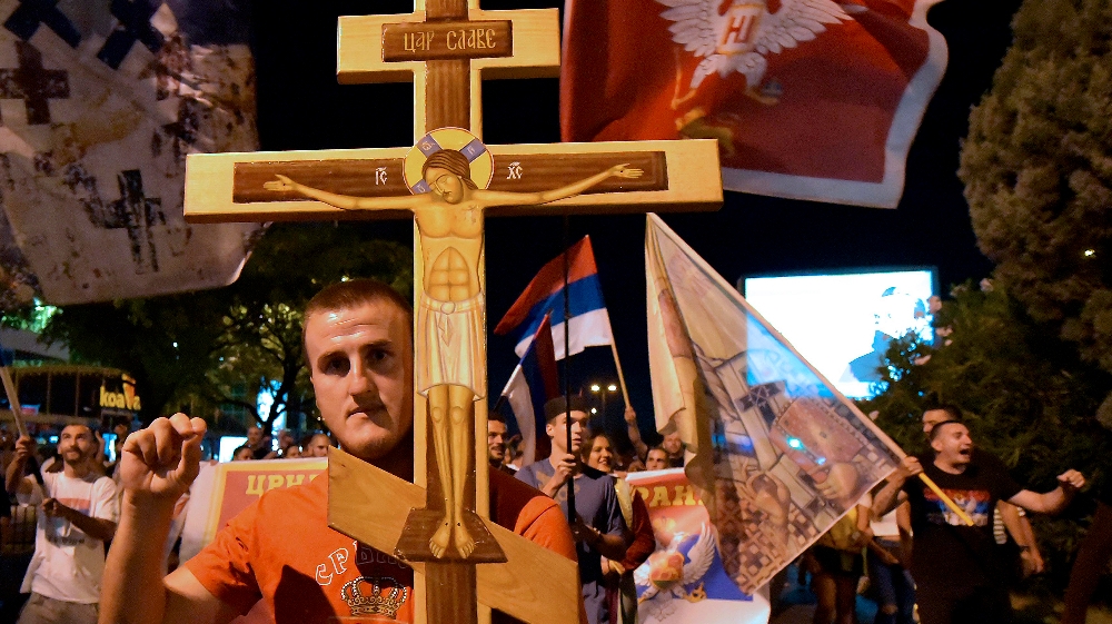 An opposition supporter holds a cross during church-led protest in Podgorica, Montenegro, Thursday, Aug. 27, 2020. Montenegro is holding a parliamentary election this weekend 