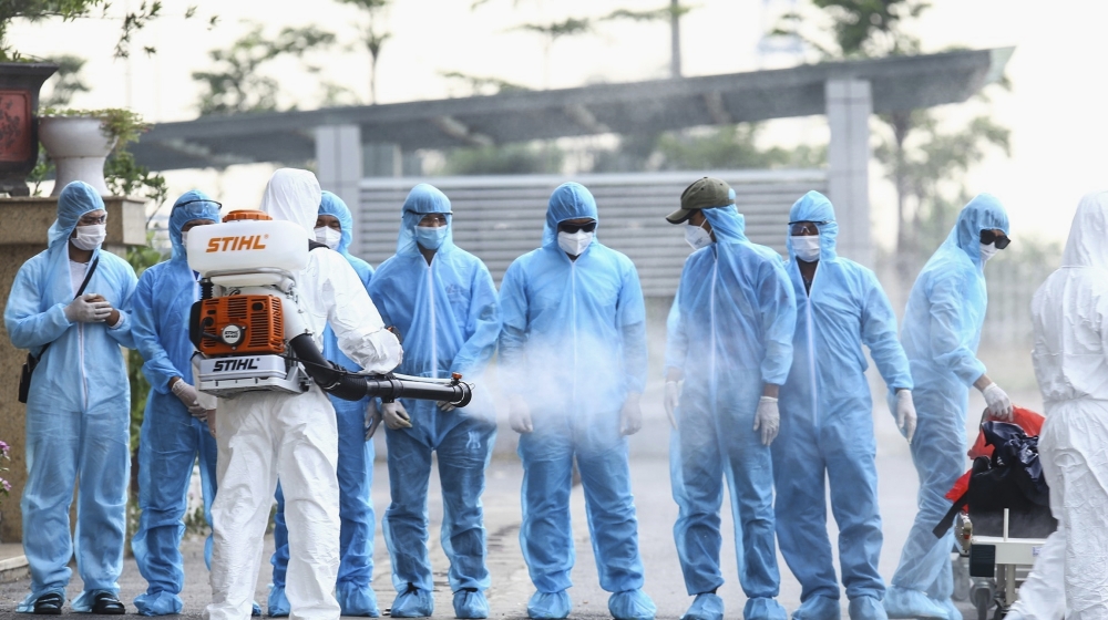 A health worker disinfects arriving Vietnamese COVID-19 patients at the national hospital of tropical diseases in Hanoi, Vietnam on Wednesday, July 29, 2020. The 129 patients who were working in Equat