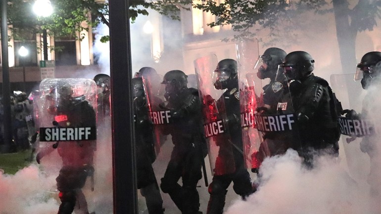 KENOSHA, WISCONSIN - AUGUST 25: As tear gas fills the air, police try to push back demonstrators near the Kenosha County Courthouse during a third night of unrest on August 25, 2020 in Kenosha, Wiscon
