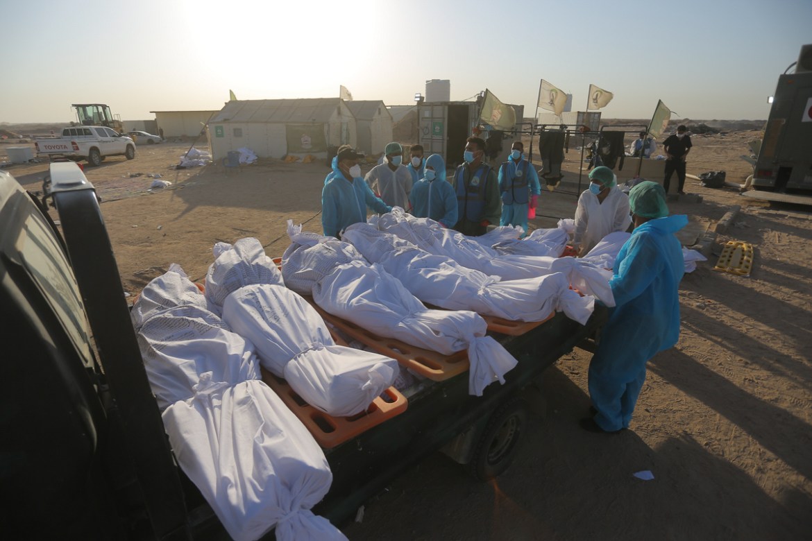 Members of the Shiite Imam Ali brigades militia load bodies of a coronavirus victims during a funeral at Wadi al-Salam cemetery near Najaf, Iraq, Monday, July 20, 2020. A special burial ground near th