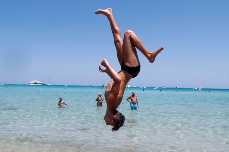 A man performs a backflip at Mondello beach, following the outbreak of the coronavirus disease (COVID-19) in Palermo, Italy, July 31, 2020. REUTERS/Guglielmo Mangiapane T