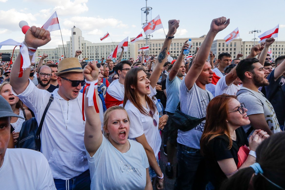 People with old Belarusian national flags shout during opposition rally in front of the government building of Minsk, Belarus, Sunday, Aug. 16, 2020. Opposition supporters whose protests have convulse