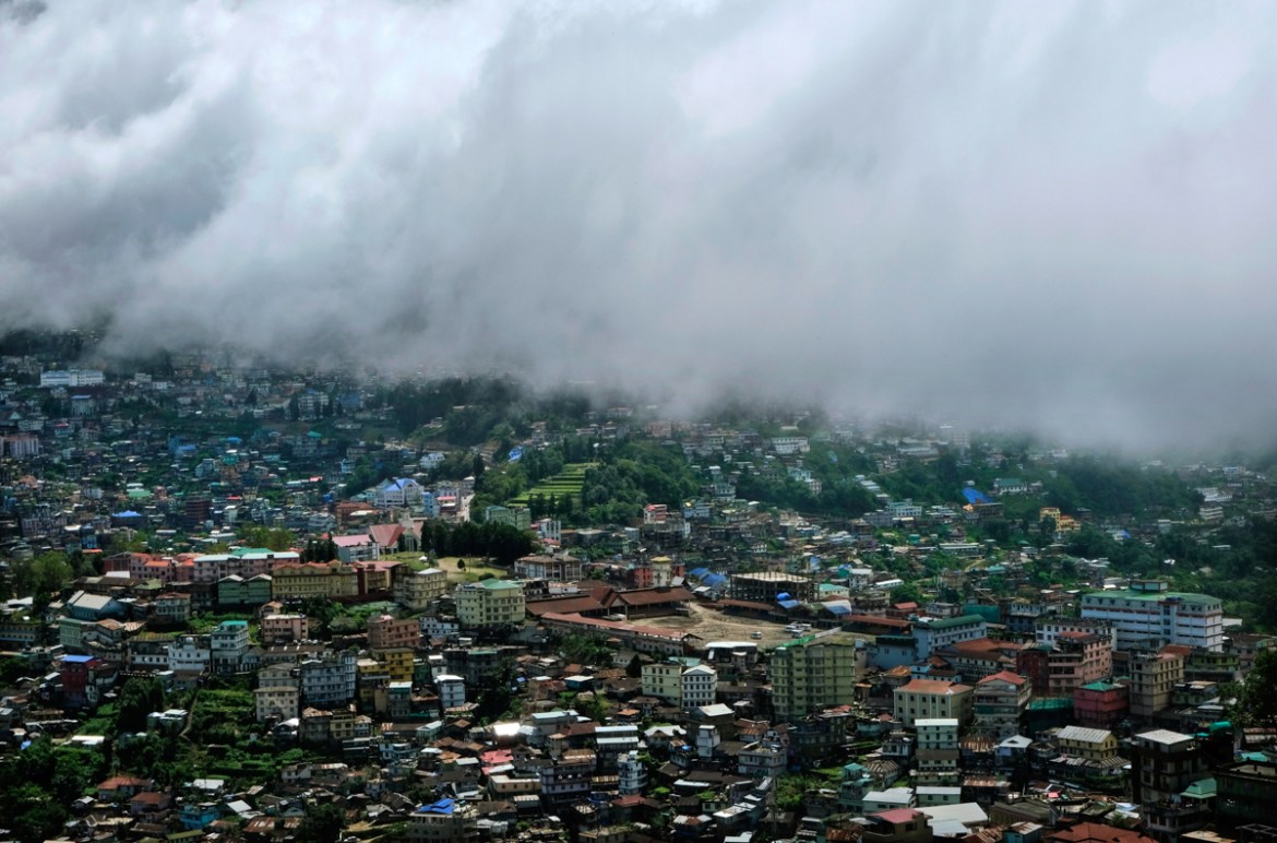 Monsoon clouds form a border over Kohima War Cemetery, green terraced lawns in center, and the area which was the main site of a bloody battle in 1944 between the Japanese and British Commonwealth f