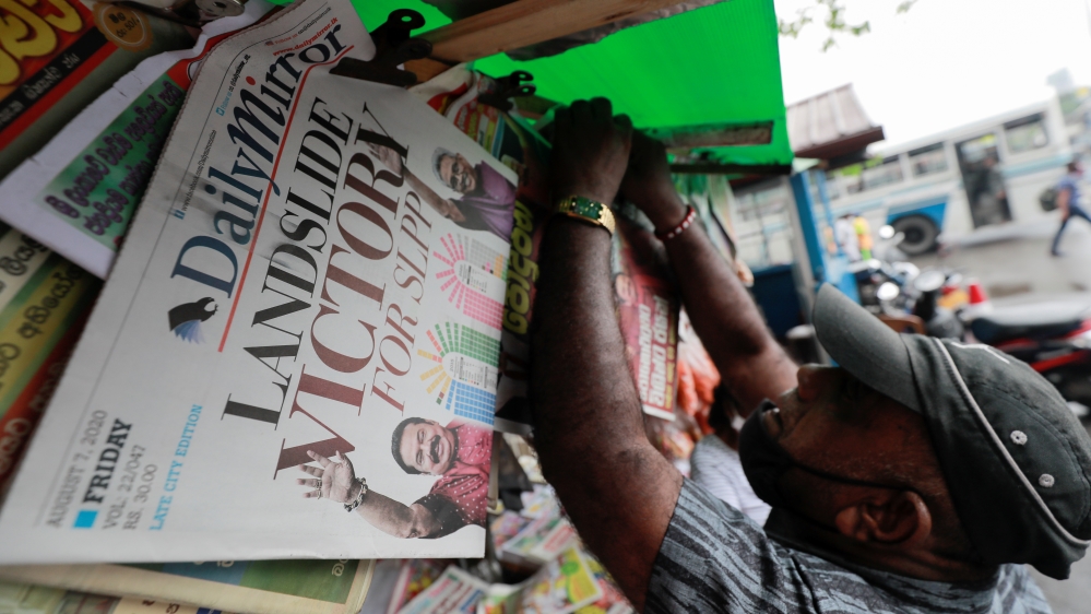 A man hangs newspapers carrying  headlines about the victory of Mahinda Rajapaksa's Sri Lanka People's Front party in the country's parliamentary election in Colombo