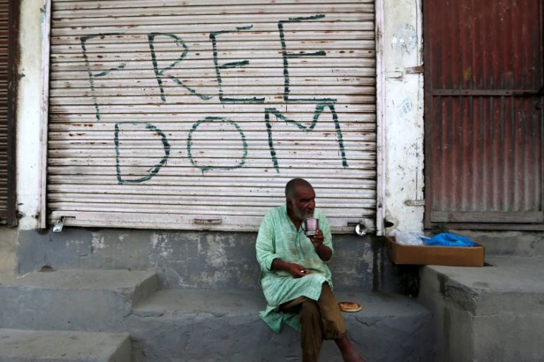 Kashmiri man drinks tea in front of a closed shop in Anchar neighbourhood in Srinagar