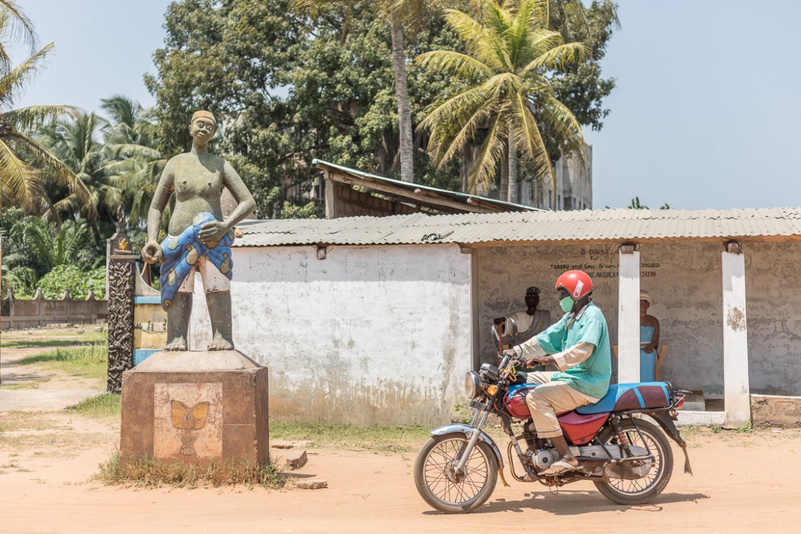 A man on a motorcycle drives past the statute in front of the Zomachi memorial square in Ouidah on August 4, 2020. - As western cities see statues of slaveholders and colonialists toppled, Benin''s coa