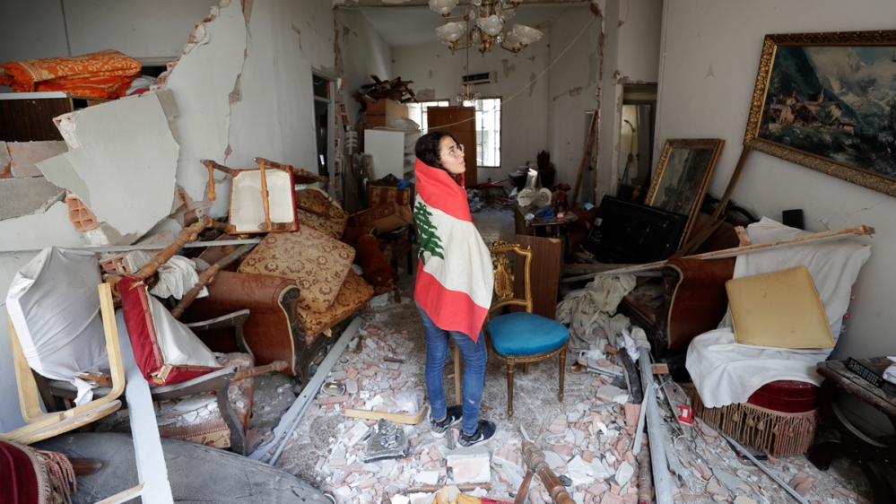 Farah Mahmoud, wrapped in Lebanese national flag, checks her parents destroyed apartment after Tuesday's explosion in the seaport of Beirut, Lebanon, Thursday, Aug. 6, 2020. The gigantic explosion in 