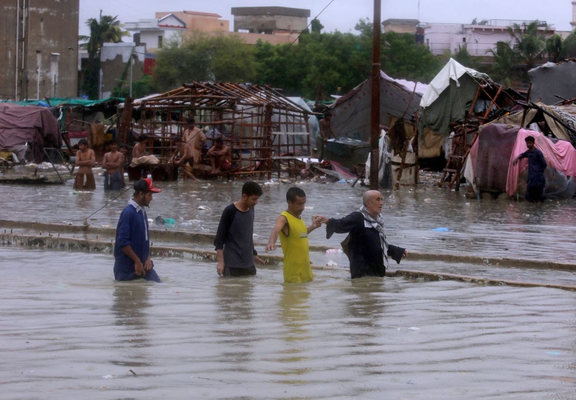 People wade through a flooded area after heavy monsoon rains, in Karachi, Pakistan, Tuesday, Aug. 25, 2020. Three days of monsoon rains have killed dozens of people and damaged hundreds of homes acros