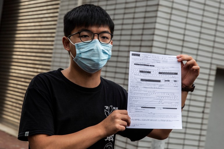 Pro-democracy activist Joshua Wong speaks to the media while holding up a bail document after leaving Central police station in Hong Kong on September 24, 2020,