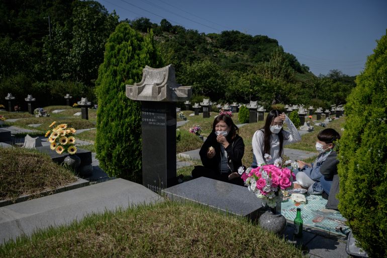 In a photo taken on September 26, 2020, a family sit before a grave after performing a traditional ceremony at a cemetery in Incheon where the the local government was encouraging people to visit cemeteries before the annual Chuseok festival in order to avoid large gatherings as part of COVID-19 coronavirus precautions. - The Chuseok festival, which runs from September 30 to October 2, is traditionally a time for family gatherings and ancestral rituals, but this year it will be starkly different with authorities urging the public to stay home instead to help contain the spread of the COVID-19 coronavirus. (Photo by Ed JONES / AFP) / TO GO WITH Health-virus-SKorea-festival,FOCUS by Sunghee Hwang